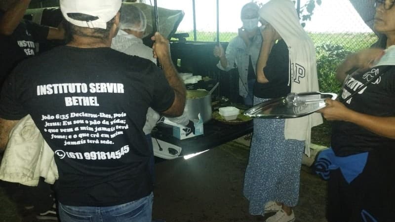 Voluntários do Instituto Servir entregando sopa